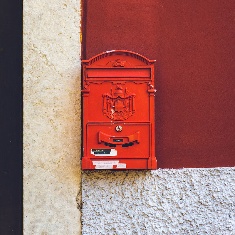 Red English metal mailbox on a wall, symbolizing email communication as part of Shopify email strategies for boosting customer engagement.