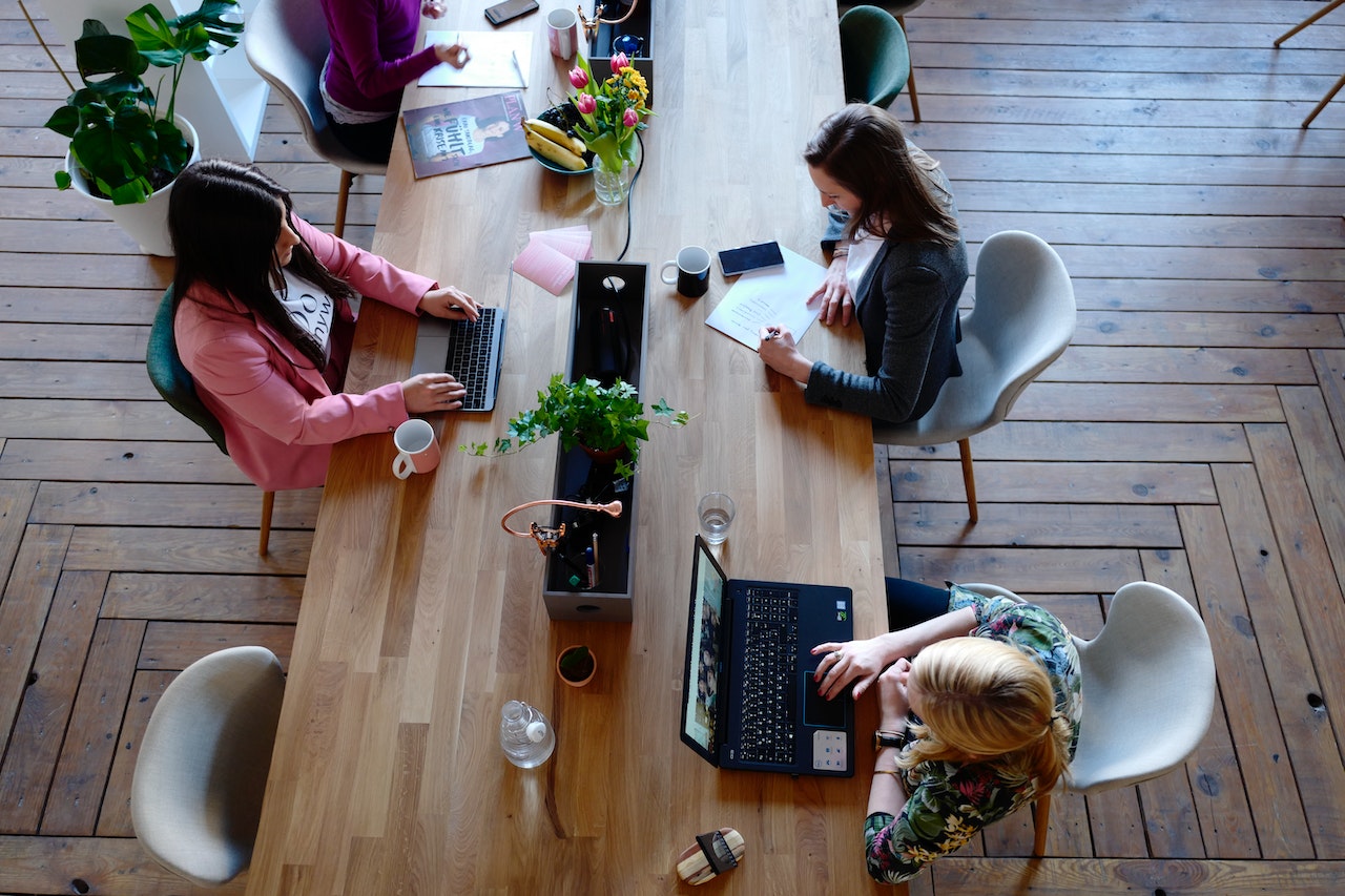 Top view of individuals working on laptops at a desk, illustrating a collaborative in-house e-commerce consultation for Shopify, as discussed in the case study on building a powerhouse.