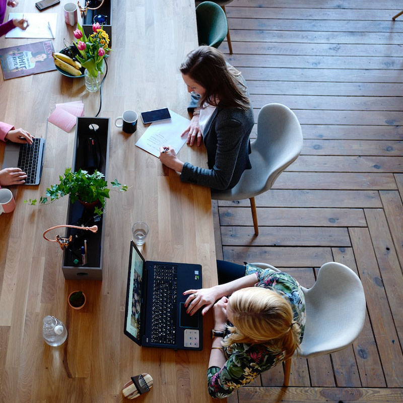 Top view of individuals working on laptops at a desk, illustrating a collaborative in-house e-commerce consultation for Shopify, as discussed in the case study on building a powerhouse.